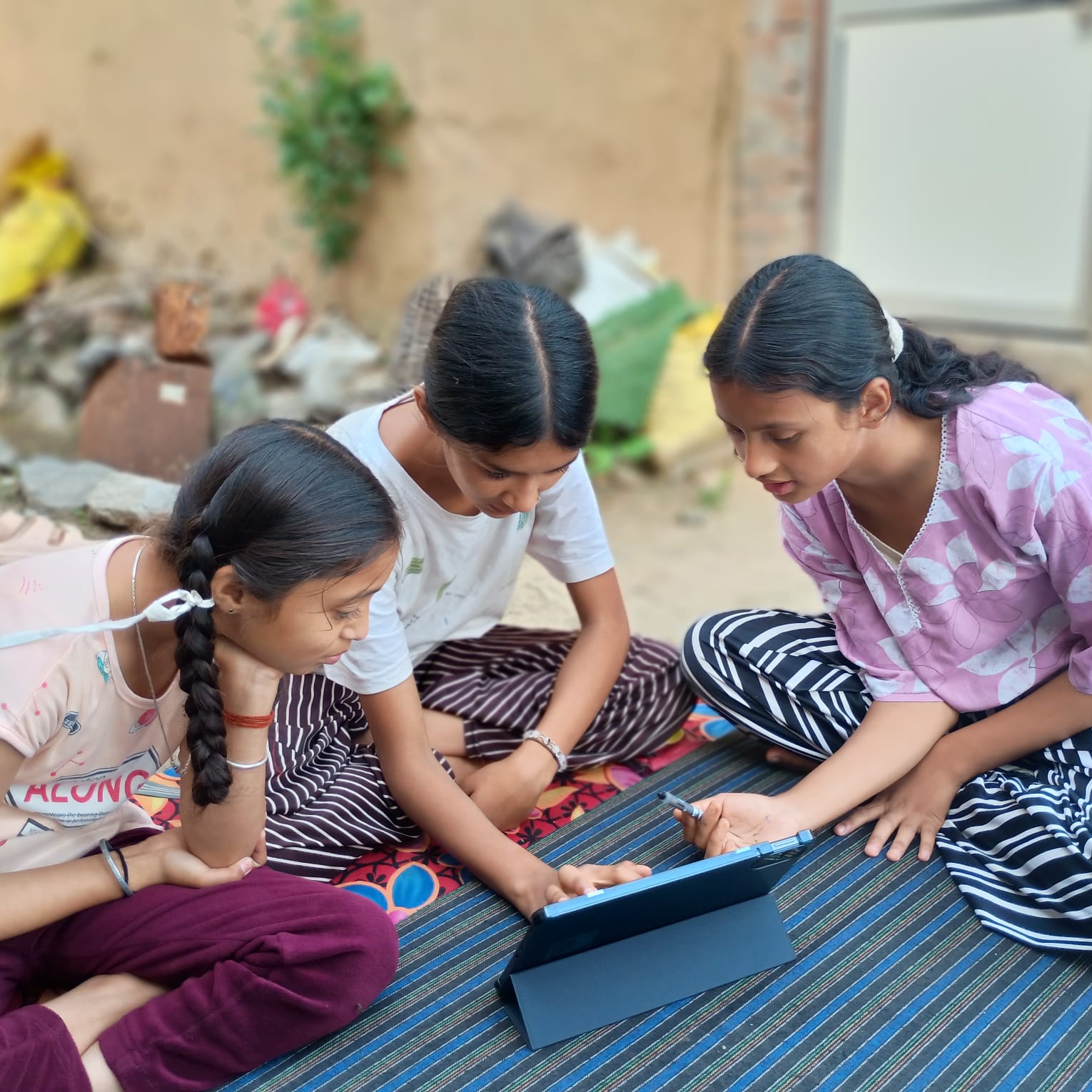 Three girls gathered around a tablet and stylus during a CyberScout activity